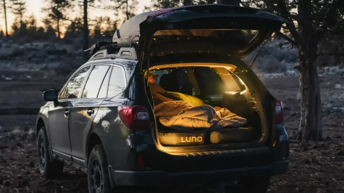 SUV with a Luno Air Pro Vehicle Mattress set up for car camping at sunrise, showing a flat sleeping platform and cozy setup inside the cargo area.