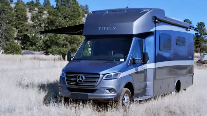 Gray Jayco Redhawk 24B Class C motorhome parked in an open field near Grand Canyon National Park, awning extended for outdoor camping setup.