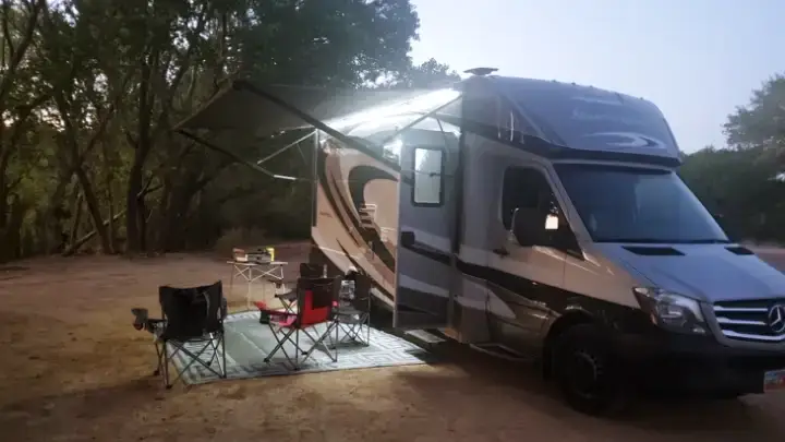 Large 2022 Forest River Forester RV parked in the Arizona desert, awning extended, surrounded by dry grass and pine-covered hills.