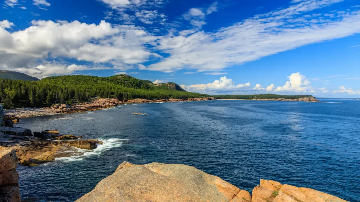 Rocky coastline and blue ocean at Acadia National Park on a clear summer day, showcasing classic scenery for visitors searching for Things to Do in Acadia National Park.