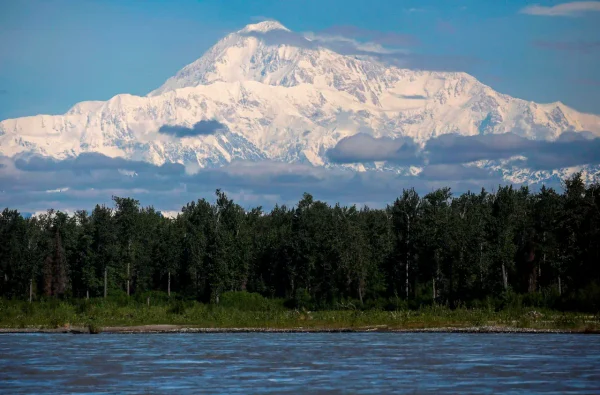 Denali mountain rising above forest and water in Alaska, representing the best time to visit Denali National Park, seasonal planning, wildlife, hiking, and tours.